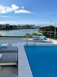 a swimming pool with two beds and a view of the water at Belmoral Corporate Suites in Townsville