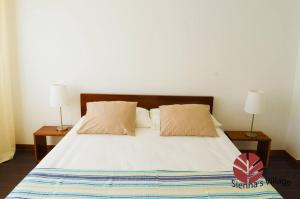 a bedroom with a bed with two night stands and two lamps at Brisa Village in São Tomé