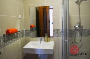 a bathroom with a sink and a shower with a mirror at Brisa Village in São Tomé