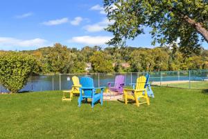 four colorful chairs sitting on the grass near a lake at Kayaks & River Access Easy Parking Beautiful in Gladwyne