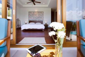 a bedroom with a bed and a table with a vase of flowers at Baan Apsara - Stunning Sea View 3 Bed Pool Villa in Choeng Mon Beach +29 photos