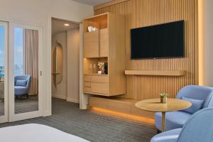 a hotel room with a television and blue chairs at Brickell Arch, a Luxury Collection Hotel, Miami in Miami