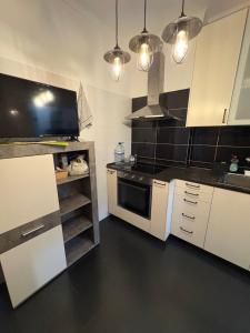 a kitchen with white cabinets and black counter tops at Quarto Espaçoso in Amora