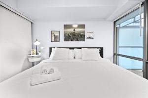 a white bedroom with a large white bed with two towels at Stylish 2BR Downtown Sanctuary - Free Parking in Toronto +19 photos