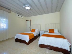 a bedroom with two beds with orange and white sheets at Hotel ALCALA in Mingueo