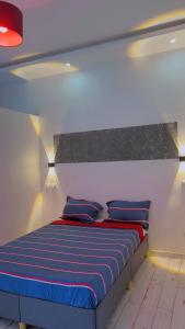 a bedroom with a bed with blue and red pillows at chez Louise in Saly Portudal