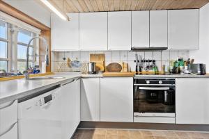 a white kitchen with white cabinets and a sink at Ferienhaus Sommer in Nordborg