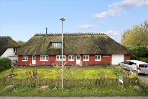 a red house with a thatched roof with a car parked in front at Ferienhaus Sommer in Nordborg +12 photos