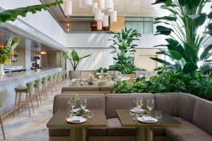 a restaurant with couches and tables and plants at Brickell Arch, a Luxury Collection Hotel, Miami in Miami