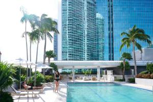 a woman standing next to a swimming pool in a hotel at Brickell Arch, a Luxury Collection Hotel, Miami in Miami