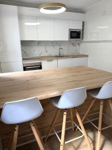 a kitchen with a wooden table and two white chairs at Entre Plazas in Cáceres +7 photos
