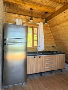 a kitchen with a stainless steel refrigerator in a cabin at Chalé Bruma in Pouso Alegre