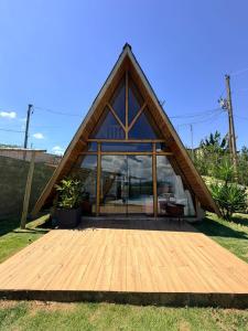 a house with a triangular roof with a wooden deck at Chalé Bruma in Pouso Alegre