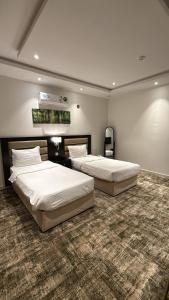 two beds in a large room with a carpet at شقق تبيان سويت للشقق المخدومة الفرع الاول in Ar Ruwanah