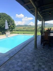 a swimming pool with a patio and an umbrella at Chalé Bruma in Pouso Alegre +9 photos