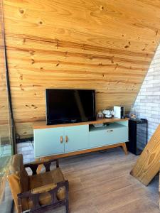a living room with a flat screen tv on a wooden wall at Chalé Bruma in Pouso Alegre