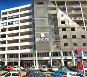 a large building with cars parked in a parking lot at Qatar Apartment in Cosenza