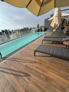 a pool on the roof of a building with chairs and umbrellas at Miraflores Loft Piscina in Lima