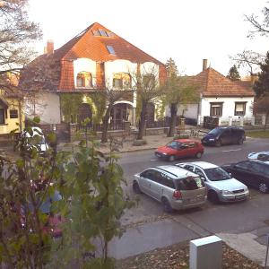 un grupo de autos estacionados frente a una casa en Mikes Apartman, en Szekszárd