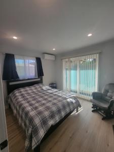 a bedroom with a bed and a chair and windows at Casa One in Winnetka
