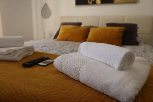 a pile of towels on a bed with a remote control at Apart Lisbon Airport in Lisbon