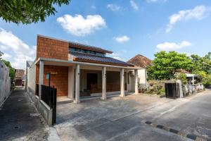 a brick house with white columns on a street at Sakabumi Home in Ngabean