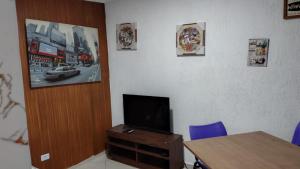a room with a table and a tv on a wall at Yellowkits in São Paulo