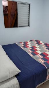 a bed with a blue blanket and a window at Yellowkits in São Paulo