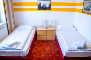 two beds in a small room with a night stand at Hotel Alser in Vienna