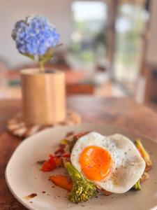 a fried egg on a plate with vegetables on a table at Casa Alta Colombia, ecolodge con vistas, Pereira in Dosquebradas +27 photos