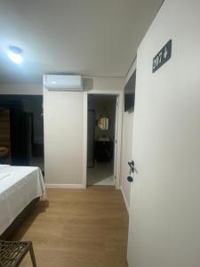 a room with a bed and a white door with a sign at Pousada Vale das Bromelias Termas do Gravatal in Gravatal +1 photo