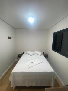 a white bedroom with a white bed with a window at Pousada Vale das Bromelias Termas do Gravatal in Gravatal