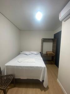 a bedroom with a white bed and a mirror at Pousada Vale das Bromelias Termas do Gravatal in Gravatal