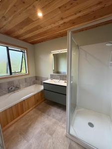 a bathroom with a tub and a sink and a shower at Whare Aorere in Collingwood