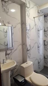 a white bathroom with a toilet and a sink at Hostal Plaza Grau in Lima