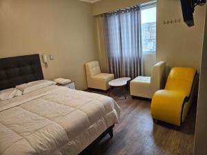 a bedroom with a bed and a chair and a window at Hostal Plaza Grau in Lima