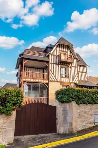 a house with a wooden gate and a fence at la villa avezard in Blonville-sur-Mer