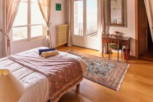 a bedroom with a bed and a table and windows at la villa avezard in Blonville-sur-Mer