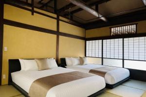 two beds in a room with two windows at 宮島 Shinwa in Miyajima