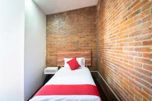a bed in a room with a brick wall at Hotel de Guadalupe, Puebla in Puebla