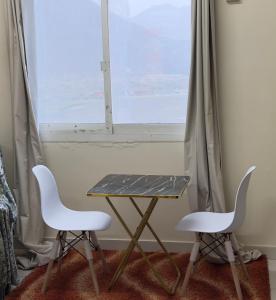 a table and two chairs in front of a window at Stay home in ‘Uqayr