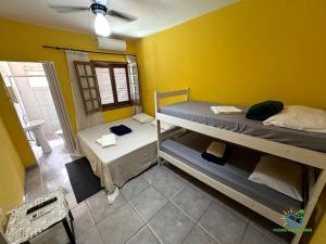 a room with two bunk beds and a yellow wall at Pousada Chácara Sonho in Hortolândia