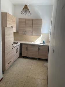 a kitchen with wooden cabinets and a sink at Aghir DJERBA Erdgeschosswohnung in Al Ḩaddādah +9 photos