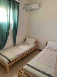 two twin beds in a room with a window at Aghir DJERBA Erdgeschosswohnung in Al Ḩaddādah