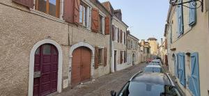 a row of cars parked on a street next to buildings at Le Petit Jaune in Orthez