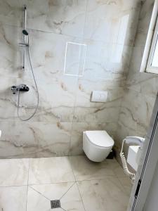 a bathroom with a toilet and a shower at Hotel corner in Bërzhitë