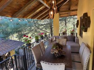 a patio with a table and chairs on a balcony at Hermosa cabaña con terraza para disfrutar Cabañas puerta del bosque Mazamitla in Mazamitla