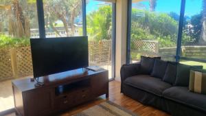 a living room with a couch and a flat screen tv at Apartment In Paradise in Hawks Nest