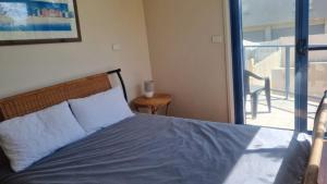 a bedroom with a bed with a view of a balcony at Apartment In Paradise in Hawks Nest +9 photos