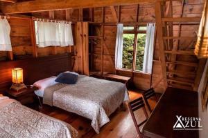 ein Schlafzimmer mit zwei Betten in einer Blockhütte in der Unterkunft Reserva Azul in Cuetzalán del Progreso
